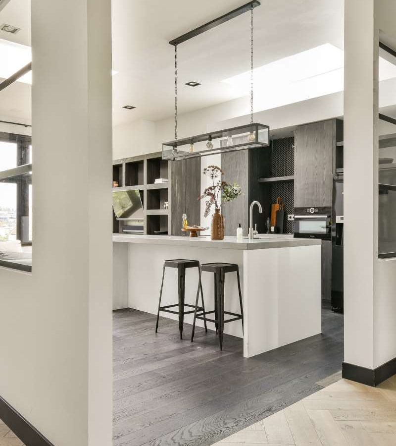 A sleek and contemporary kitchen featuring a minimalist aesthetic with dark cabinetry, light countertops, and an open layout that enhances space and functionality.